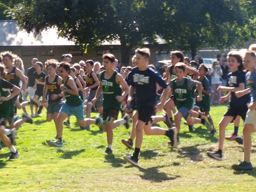 A boys track and field team running right to left 